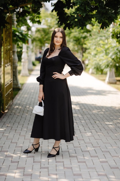 uma mulher de vestido preto está em uma calçada de tijolos