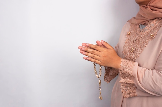 Foto uma mulher de vestido rosa está rezando com uma cruz na mão.