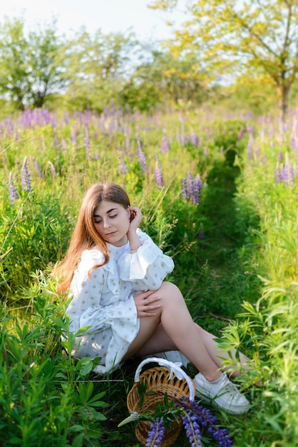 Uma mulher de vestido sentada ao lado de um caminho em um campo de lúpulos