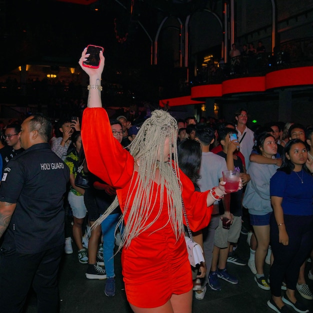 Uma mulher de vestido vermelho está segurando um celular na mão.