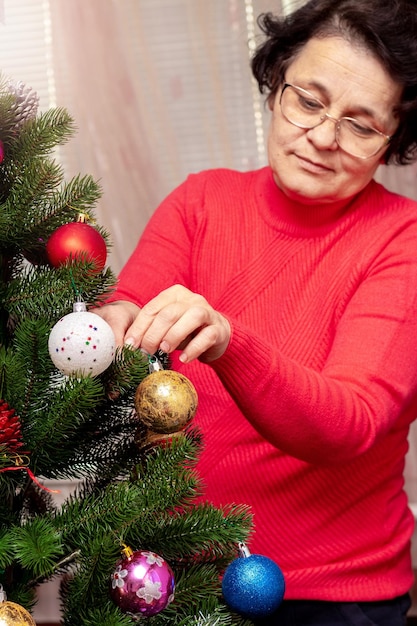 Uma mulher decora uma árvore de Natal e Ano Novo Preparação para o Natal e Ano Novo