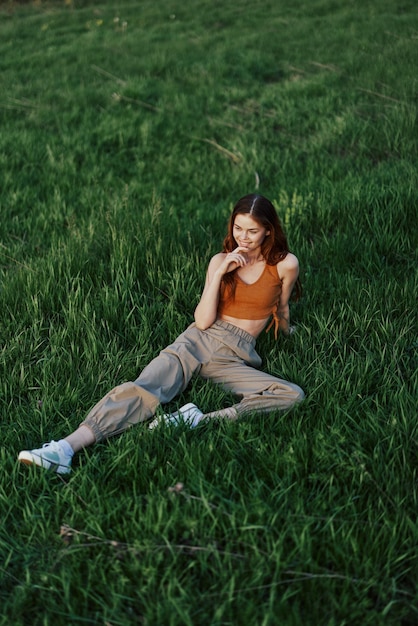Uma mulher deita-se na grama fresca da primavera em um parque sem mosquitos ou carrapatos e gosta de relaxar enquanto assiste ao pôr do sol O conceito de recreação ao ar livre segura