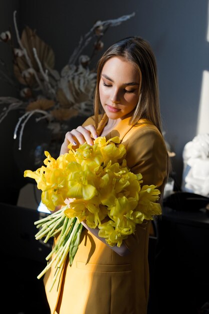 Foto uma mulher dentro de casa segurando um buquê de flores amarelas 4654