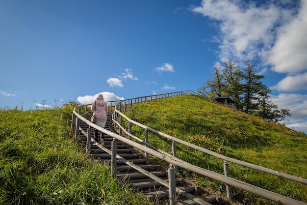 Uma mulher desce uma escada de madeira em um campo gramado.