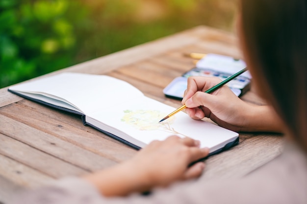 Uma mulher desenhando e pintando um quadro de árvore com aquarela