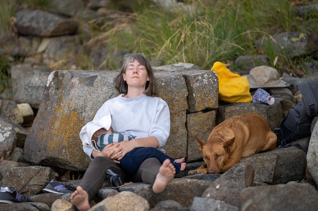 Uma mulher dorme em uma pedra com seu cachorro.