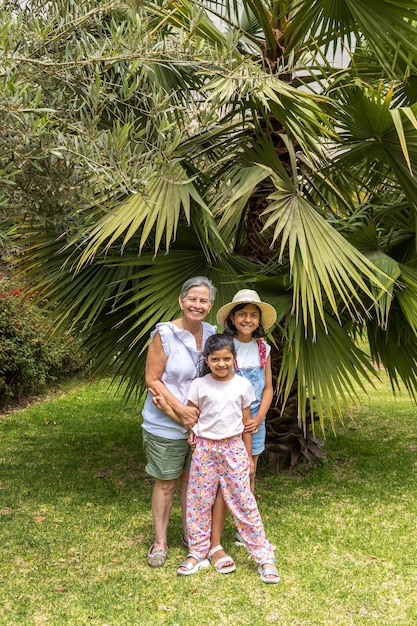 Uma mulher e duas crianças estão posando na frente de uma palmeira