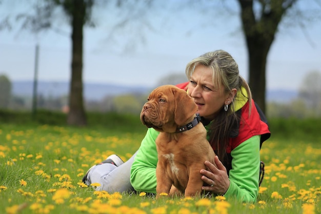 Uma mulher e seu cachorro deitado na grama