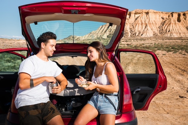 Uma mulher e um homem comendo e conversando em um carro enquanto viajavam no deserto de bardenas reales, navarra, país basco.