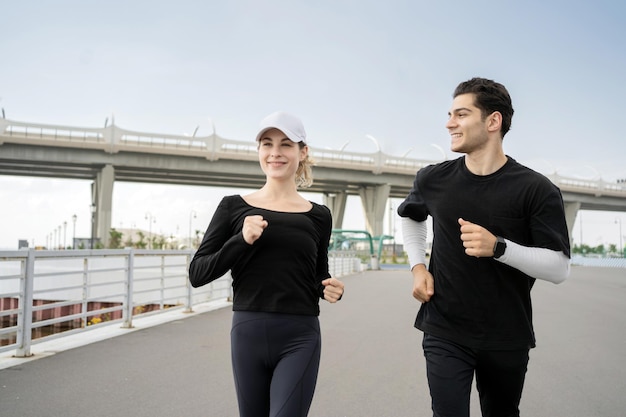 Uma mulher e um homem estão correndo fazendo fitness na rua