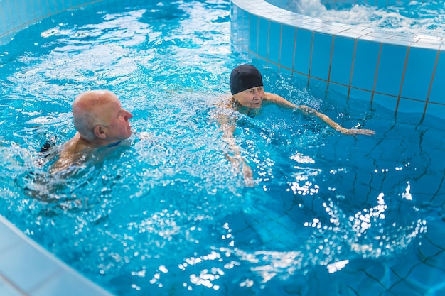 Uma mulher e um homem estão em uma piscina com ladrilhos azuis.