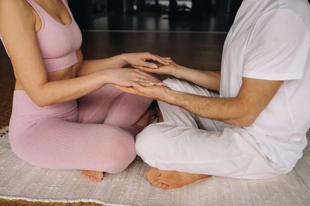 Uma mulher e um homem estão envolvidos em meditação par de mãos dadas no ginásio