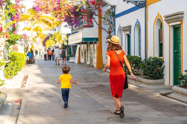 Foto uma mulher e uma criança caminham por uma rua com muitas lojas