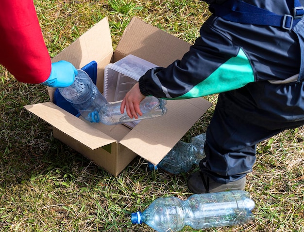 Uma mulher e uma criança coletam plástico sujo em uma caixa de papel educação ecológica