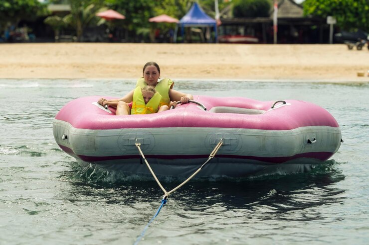 Foto uma mulher e uma criança em coletes salva-vidas sentam-se em um barco de banana inflável rosa flutuando