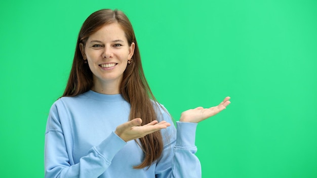 Foto uma mulher em close em um fundo verde aponta para o lado