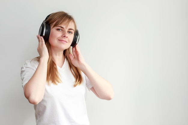 Uma mulher em fones de ouvido ouve música em um fundo branco