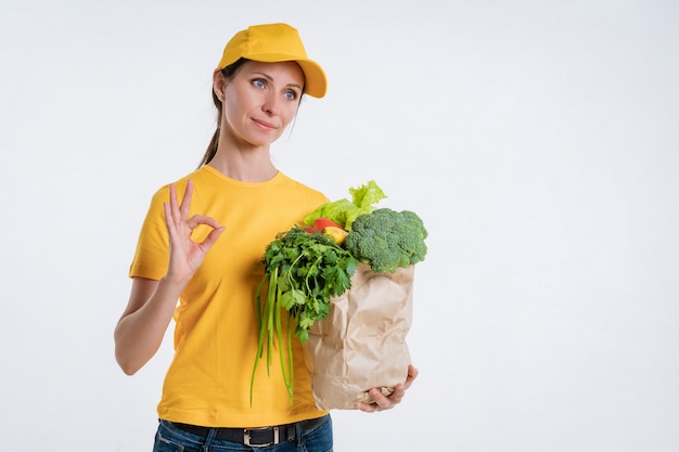 Foto uma mulher em roupas amarelas, entregando um pacote de comida, sobre um fundo branco