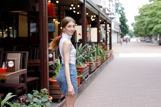 Uma mulher em roupas casuais sorri e caminha pela rua