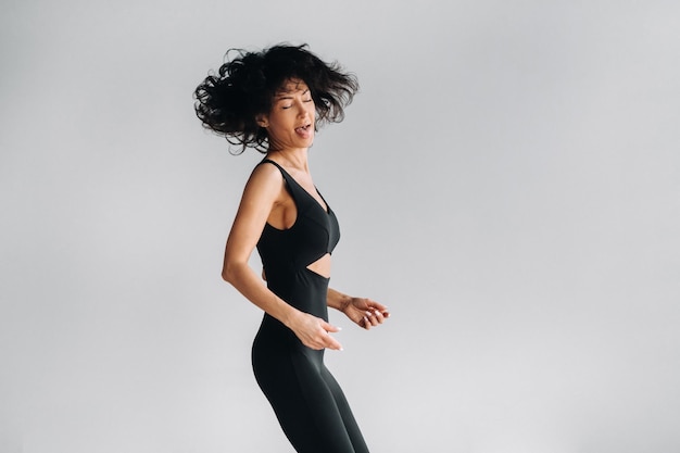 Uma mulher em roupas esportivas pretas está envolvida em meditação kali dinâmica no salão de Yoga
