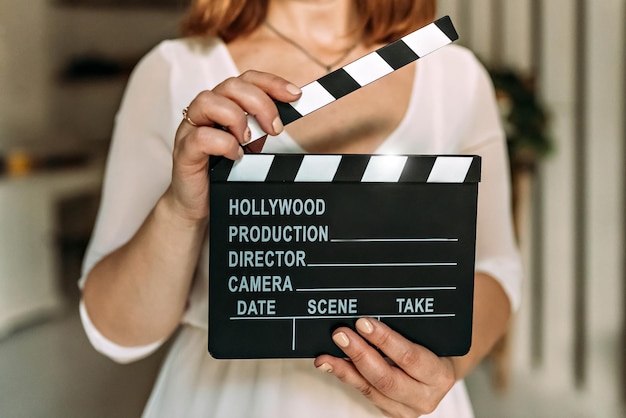 Uma mulher em suas mãos segura um tabuleiro preto com um clapperboard enquanto filma um vídeo de outono