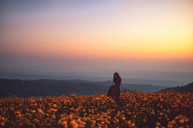 Uma mulher em um belo jardim de flores no topo da colina antes do nascer do sol