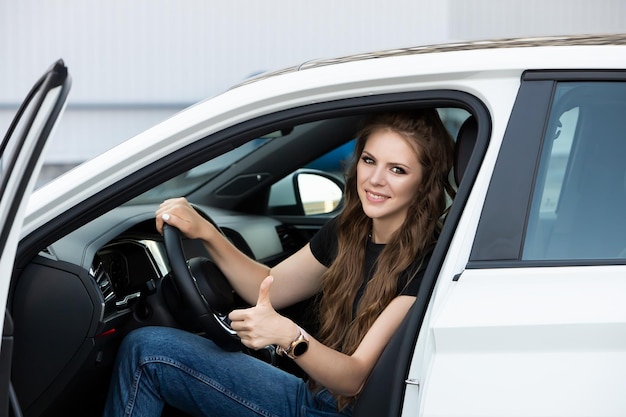 Uma mulher em um carro branco com um sinal de polegar para cima