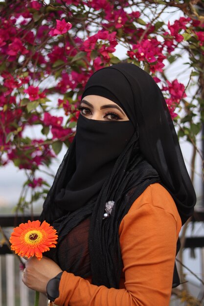 Foto uma mulher em um hijab e uma flor