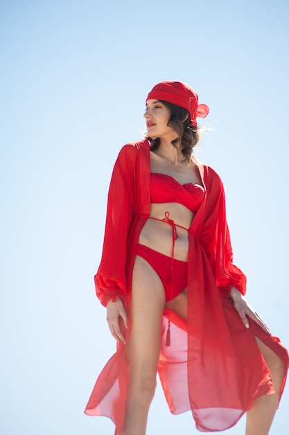 Uma mulher em um maiô vermelho está em uma praia.