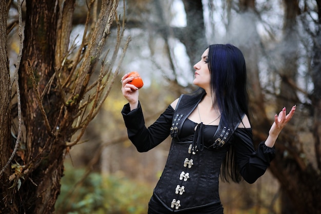Uma mulher em um traje de bruxa em uma floresta densa em um ritual