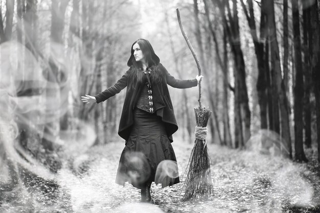 Uma mulher em um traje de bruxa em uma floresta densa em um ritual