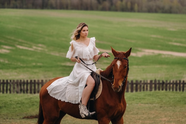 Uma mulher em um vestido branco andando a cavalo em um campo