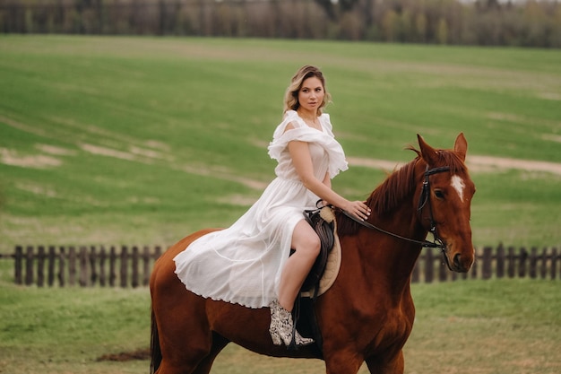 Uma mulher em um vestido branco andando a cavalo em um campo