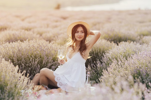 Uma mulher em um vestido branco senta-se em um campo de lavanda.