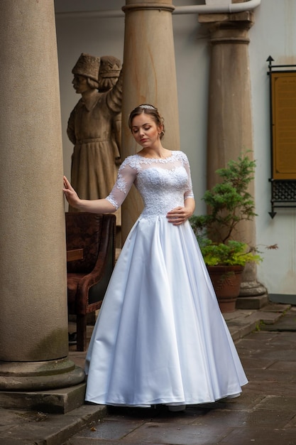 Uma mulher em um vestido de noiva branco fica na frente de uma coluna