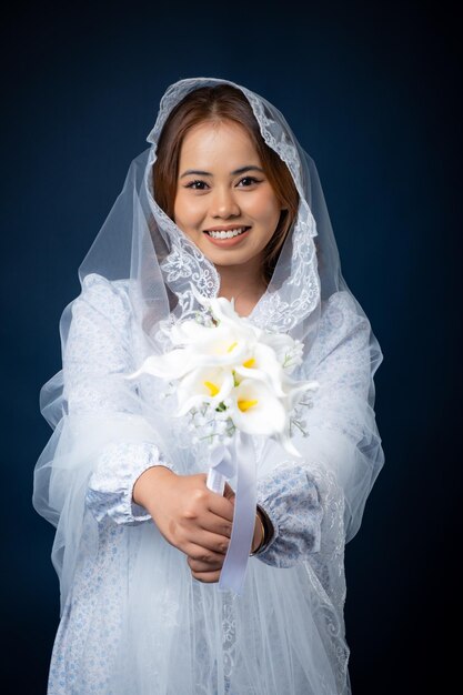 Uma mulher em um vestido de noiva segura um buquê de flores.