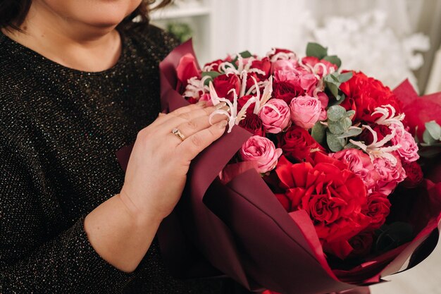 Uma mulher em um vestido escuro com um buquê de flores em um interior brilhante de Natal.