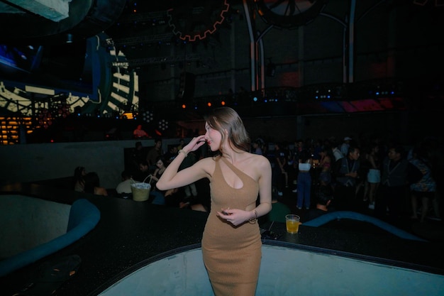 Uma mulher em um vestido fica em frente a uma tela grande que diz "a palavra clube" nela