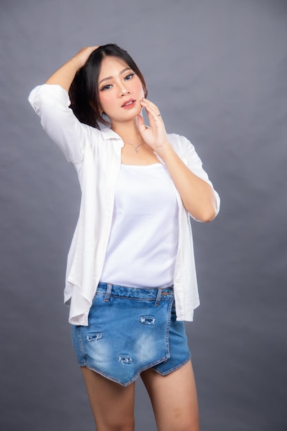 Uma mulher em uma camisa branca e saia jeans posa para um penteado de banner de loja de moda promocional de fotos