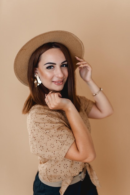 uma mulher em uma camisa de chapéu com posando em um fundo bege