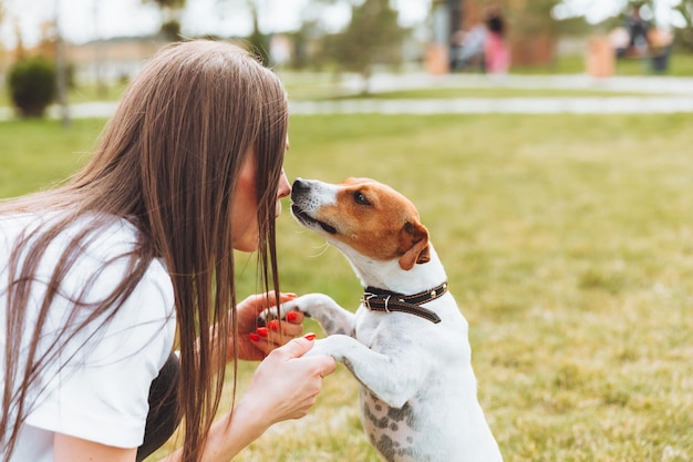 Uma mulher em uma camiseta branca e jeans abraça seu cachorro Jack Russell Terrier na natureza no parque Leais melhores amigos desde a infância Estilo de vida