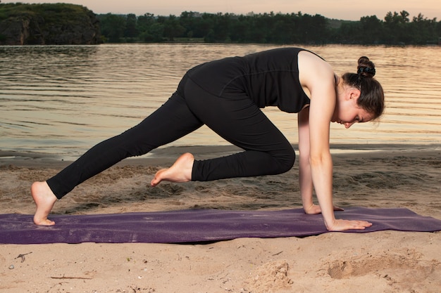 Uma mulher em uma pose de prancha com uma perna levantada.