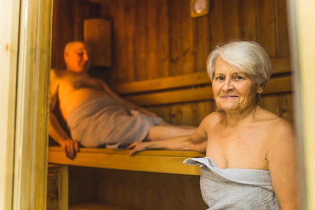 Uma mulher em uma sauna com um homem ao fundo