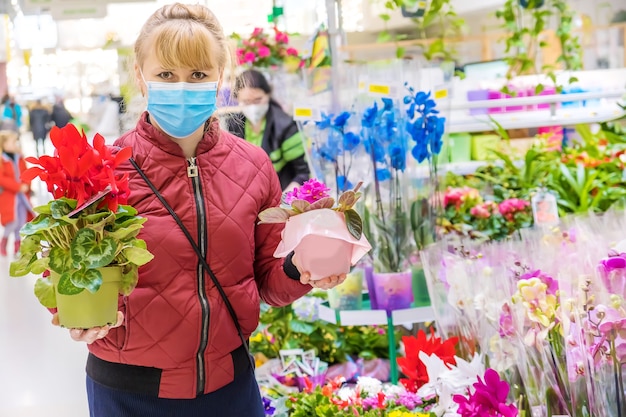 Uma mulher escolhe uma flor em um vaso de uma floricultura