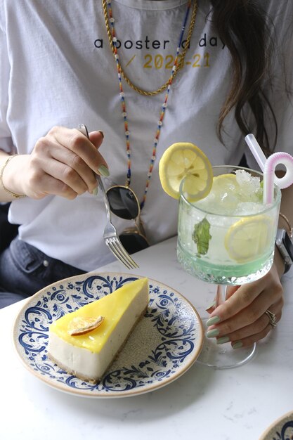 Foto uma mulher está a cortar uma fatia de bolo com uma fata de limão.