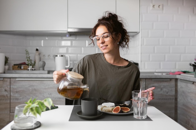 Foto uma mulher está bebendo chá em uma cozinha.