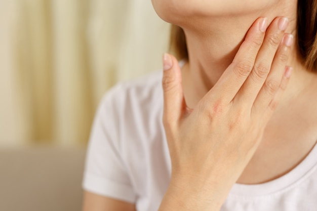 Uma mulher está com dor de garganta causada pela gripe e COVID-19.