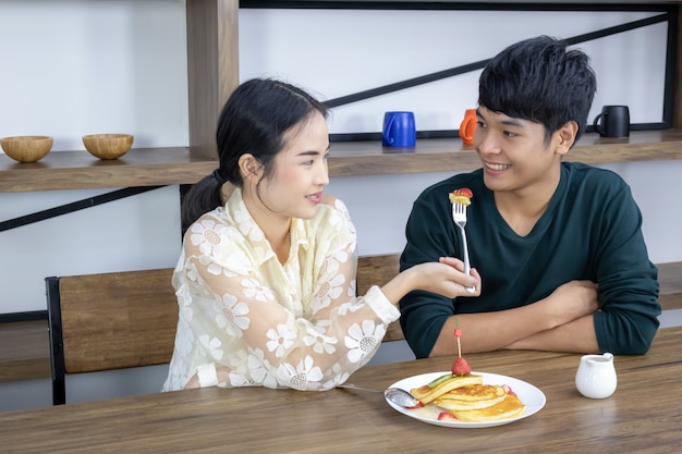 Uma mulher está dando uma torta de morango para um homem.