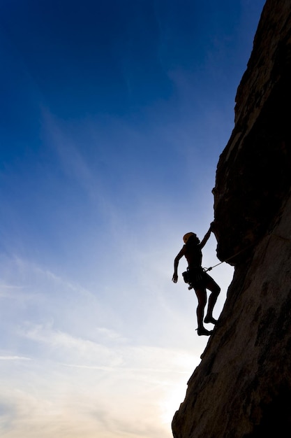 uma mulher está de pé em uma rocha com um fundo de céu