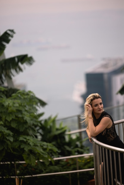 Uma mulher está em uma varanda com vista para o horizonte de Singapura.